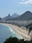 a crowded beach with mountains in the background