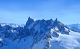 a mountain range covered in snow under a blue sky