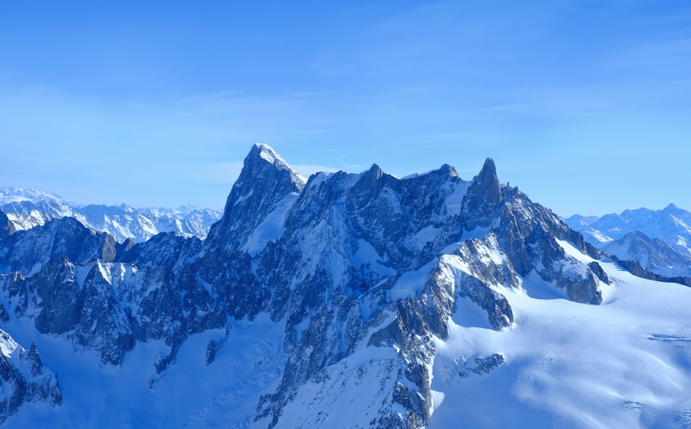 a mountain range covered in snow under a blue sky