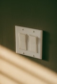 a white light switch sitting on top of a wall