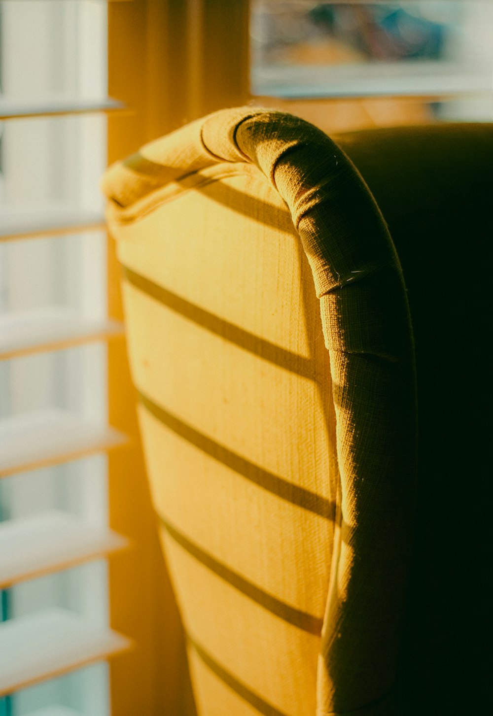 a close up of a yellow chair near a window