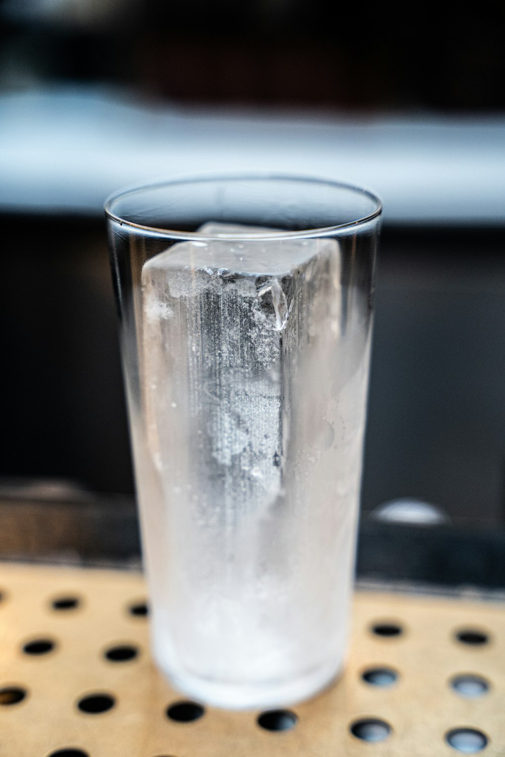 a glass of ice sitting on top of a wooden table