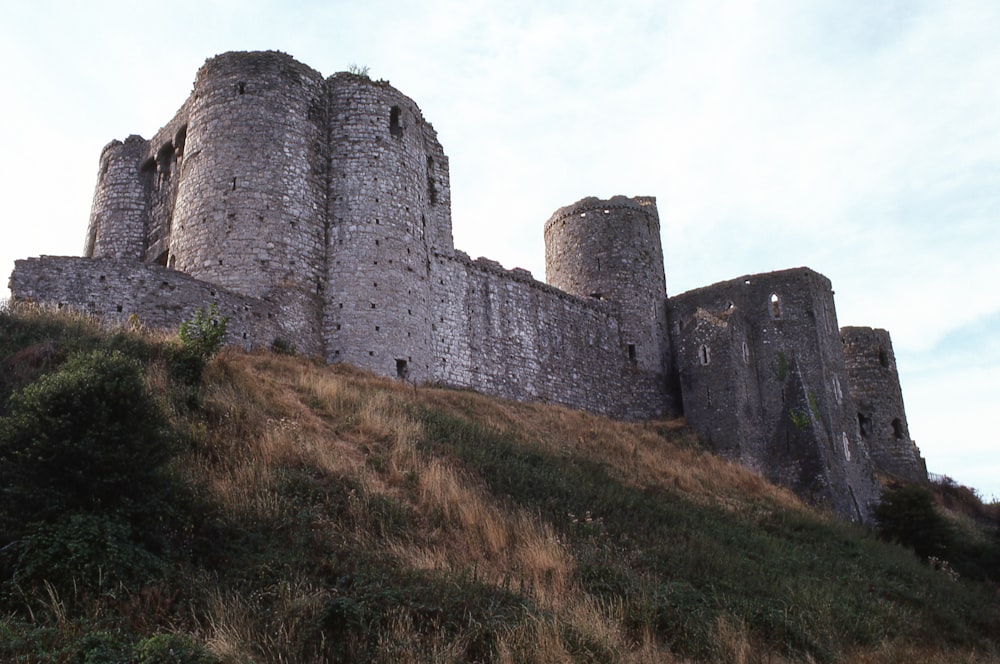 Un grande castello seduto in cima a una collina verde e lussureggiante