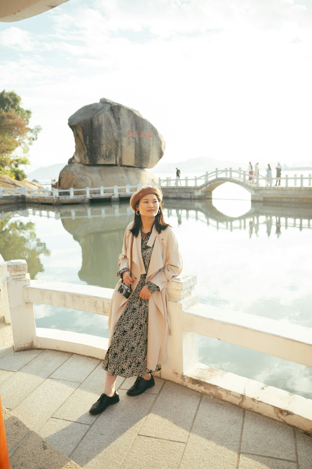 a woman standing on a bridge next to a body of water