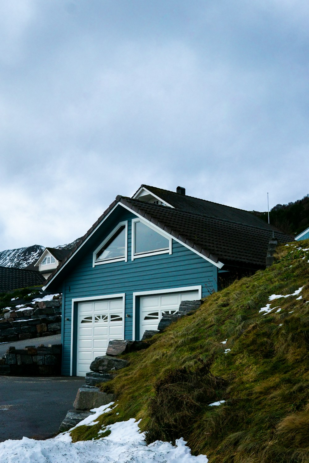 a blue house on a hill with snow on the ground