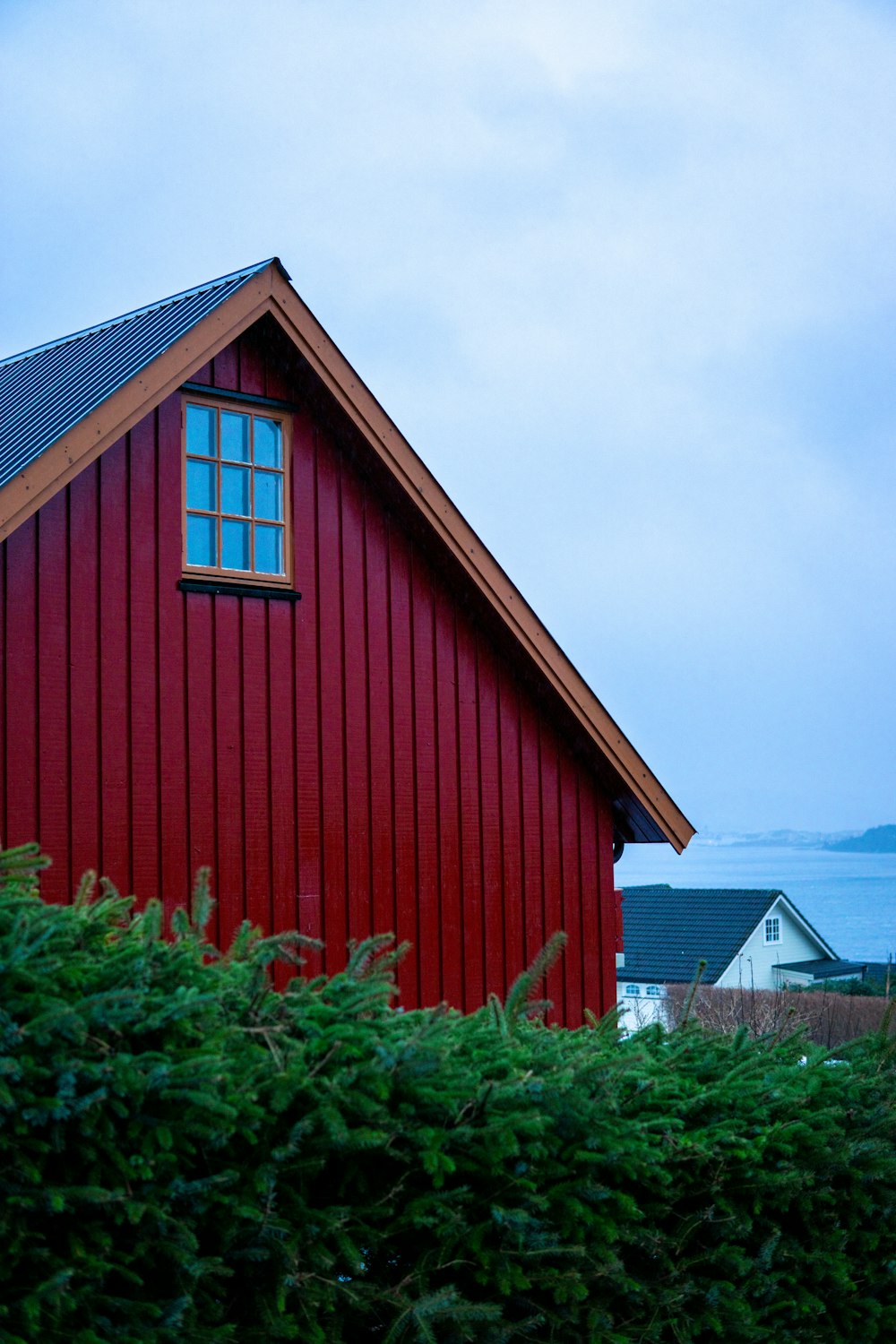 a red house with a blue sky and water in the background