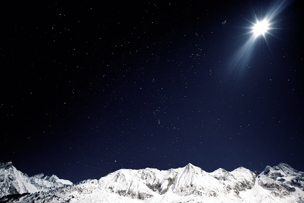 a bright star shines above a snowy mountain range