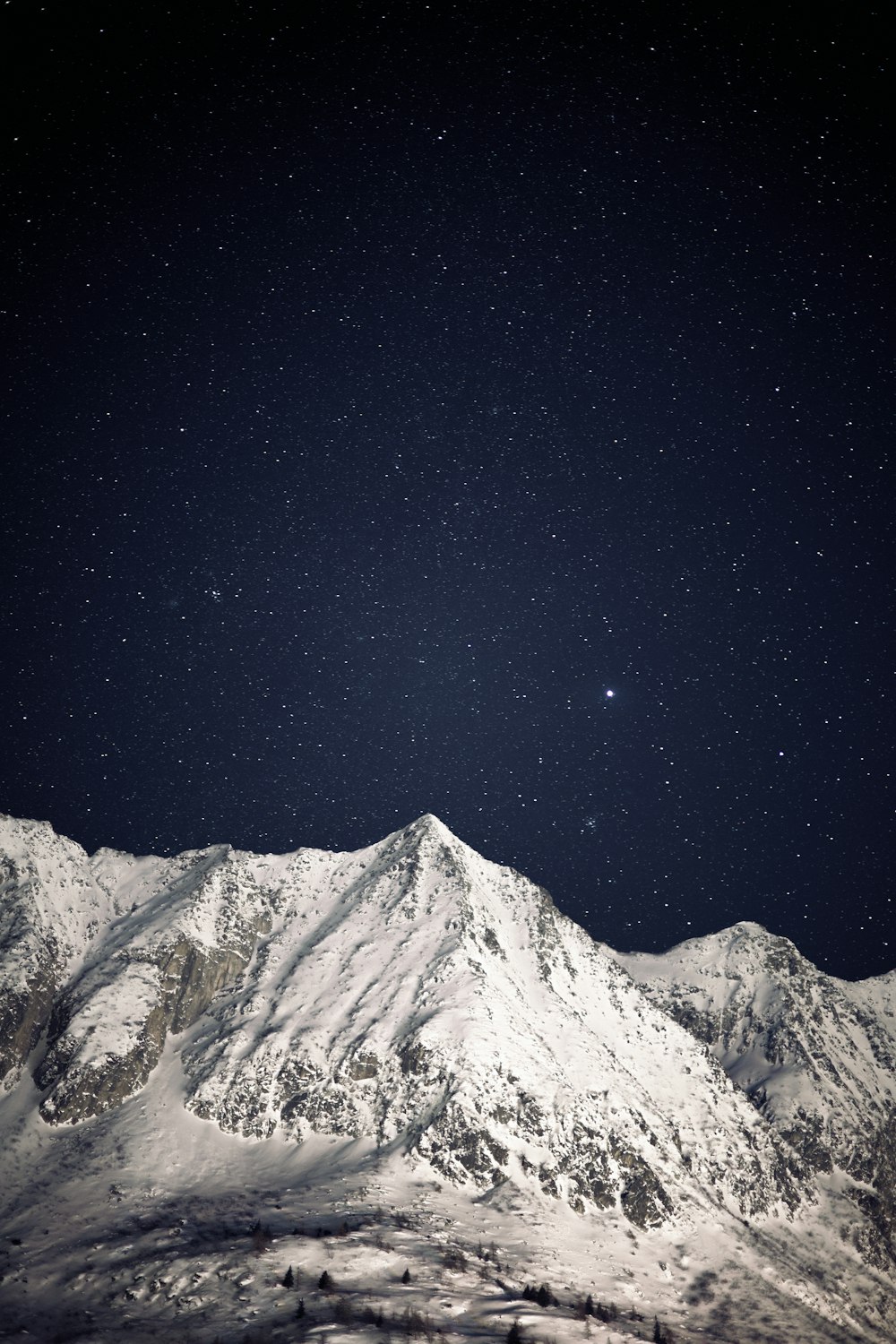 una montaña cubierta de nieve bajo un cielo nocturno