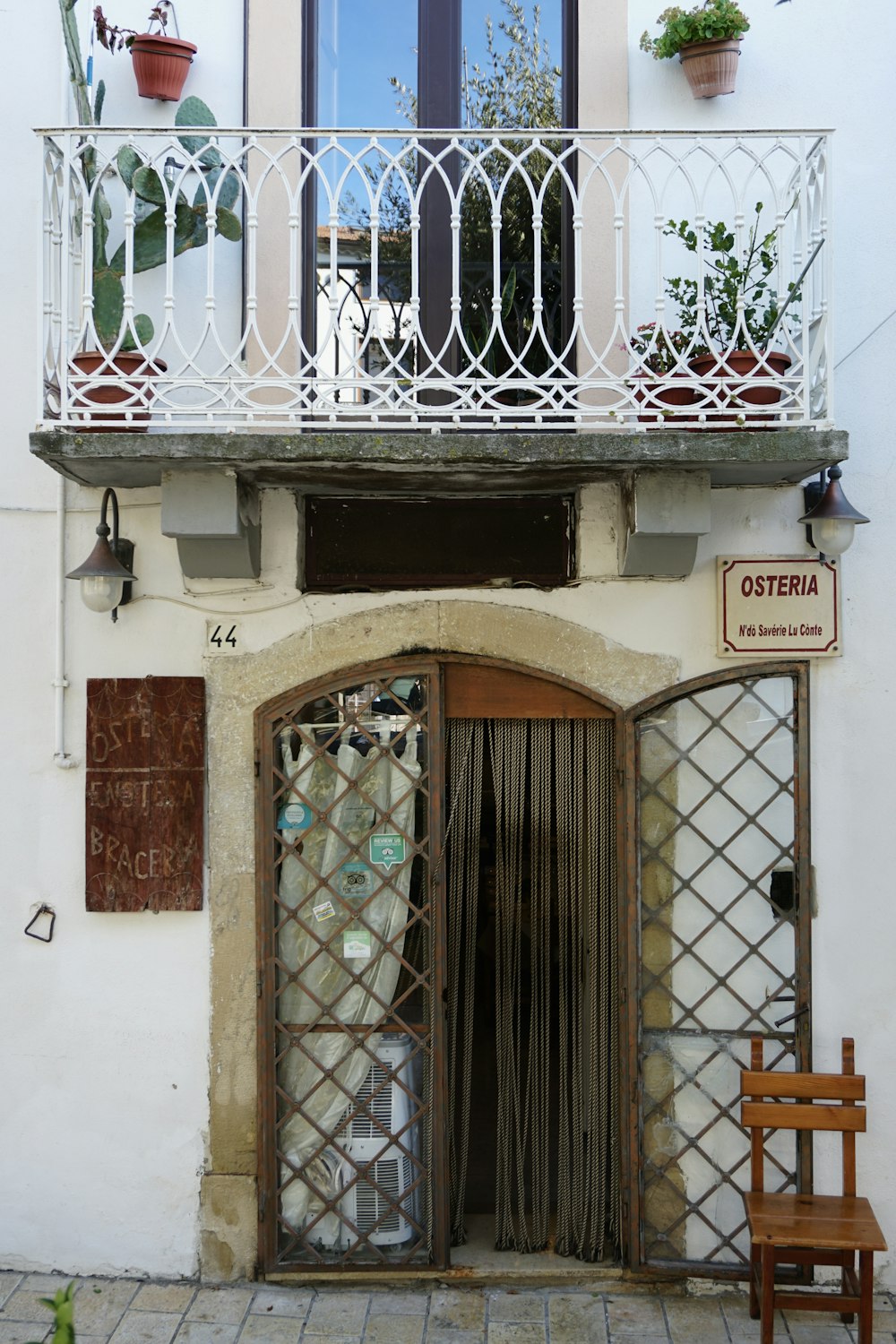 a white building with a balcony and a wooden chair