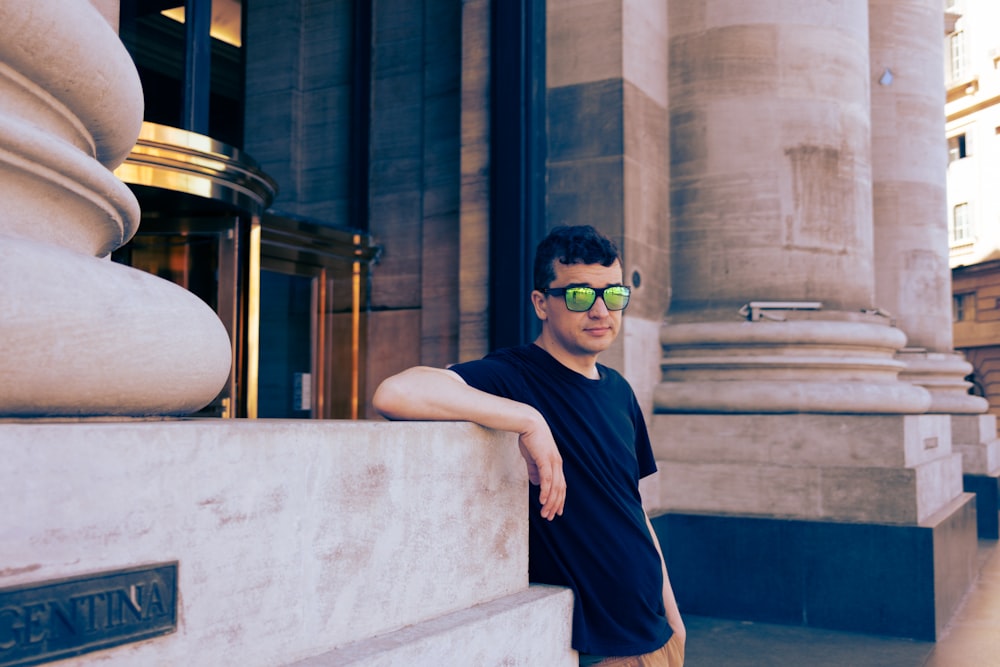 a man in sunglasses leaning against a wall