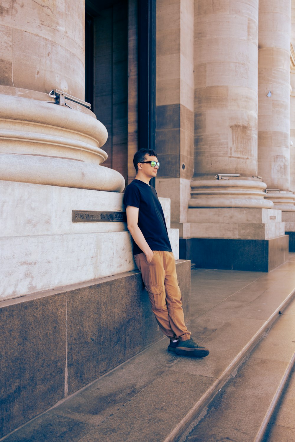 a man leaning against a wall in front of a building