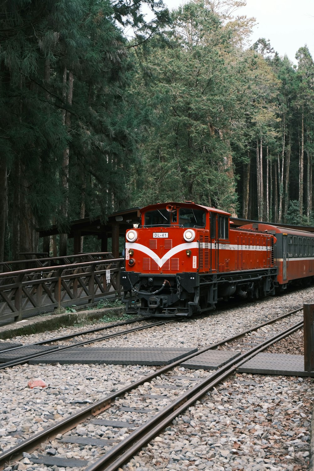 a red train traveling down train tracks next to a forest