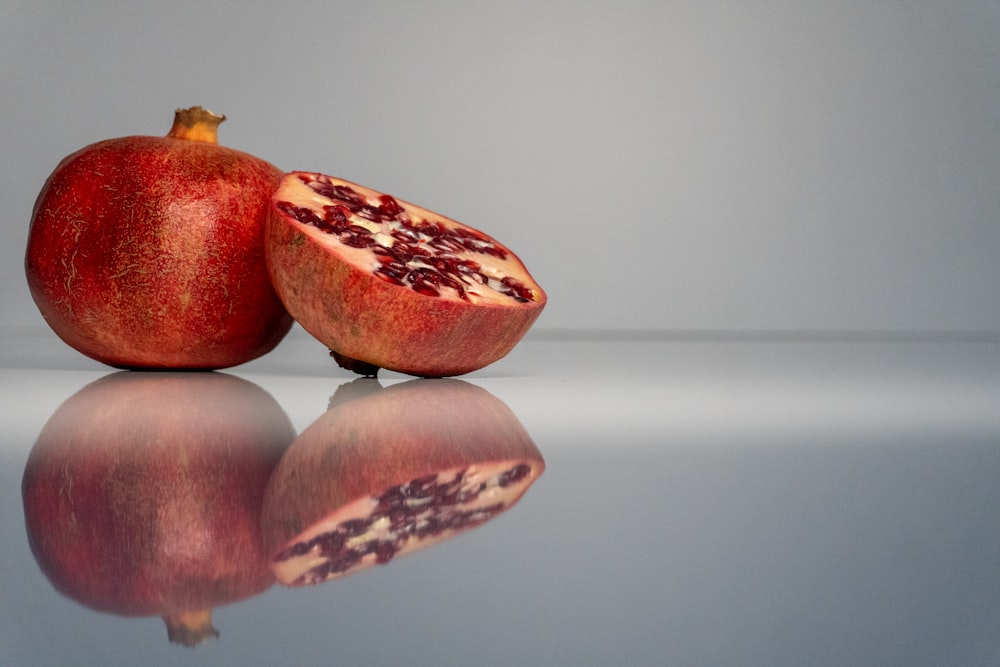 a pomegranate cut in half on a reflective surface