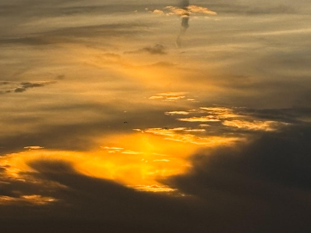 Un avión volando a través de un cielo nublado al atardecer