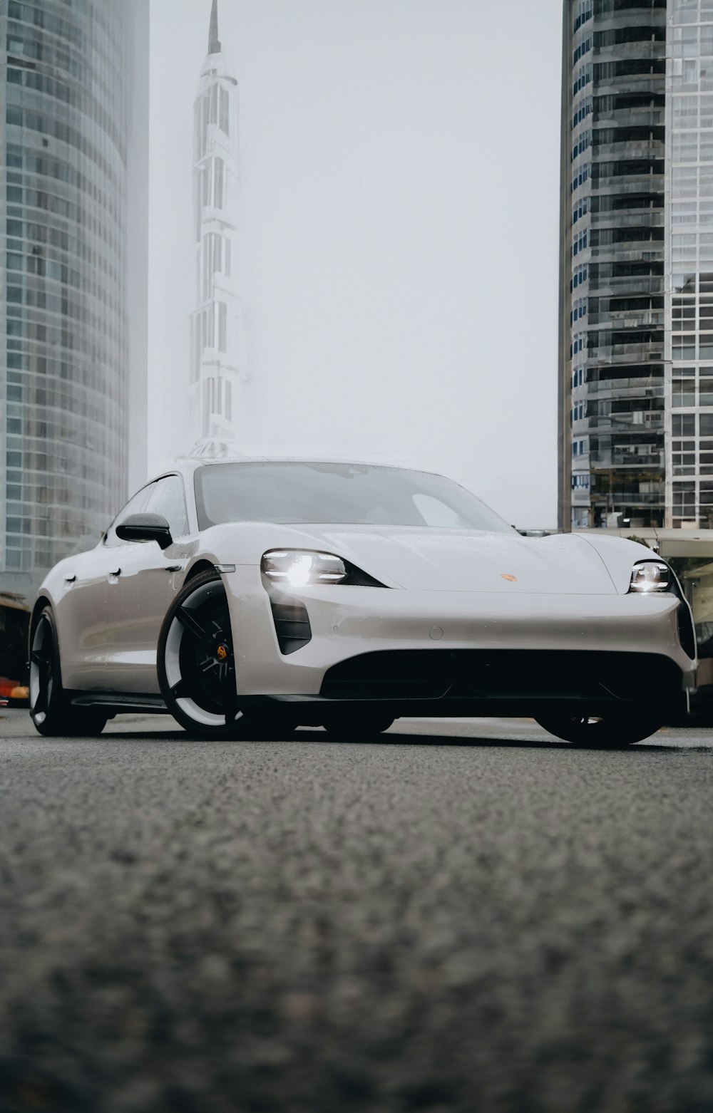 a white sports car parked in front of a tall building