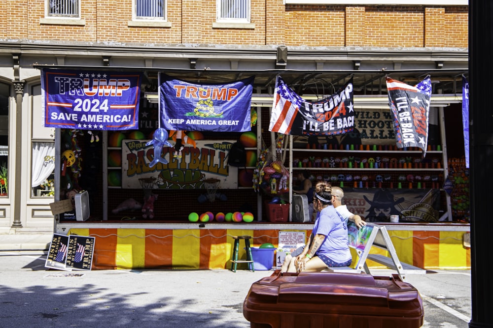 a man sitting on top of a suitcase in front of a store