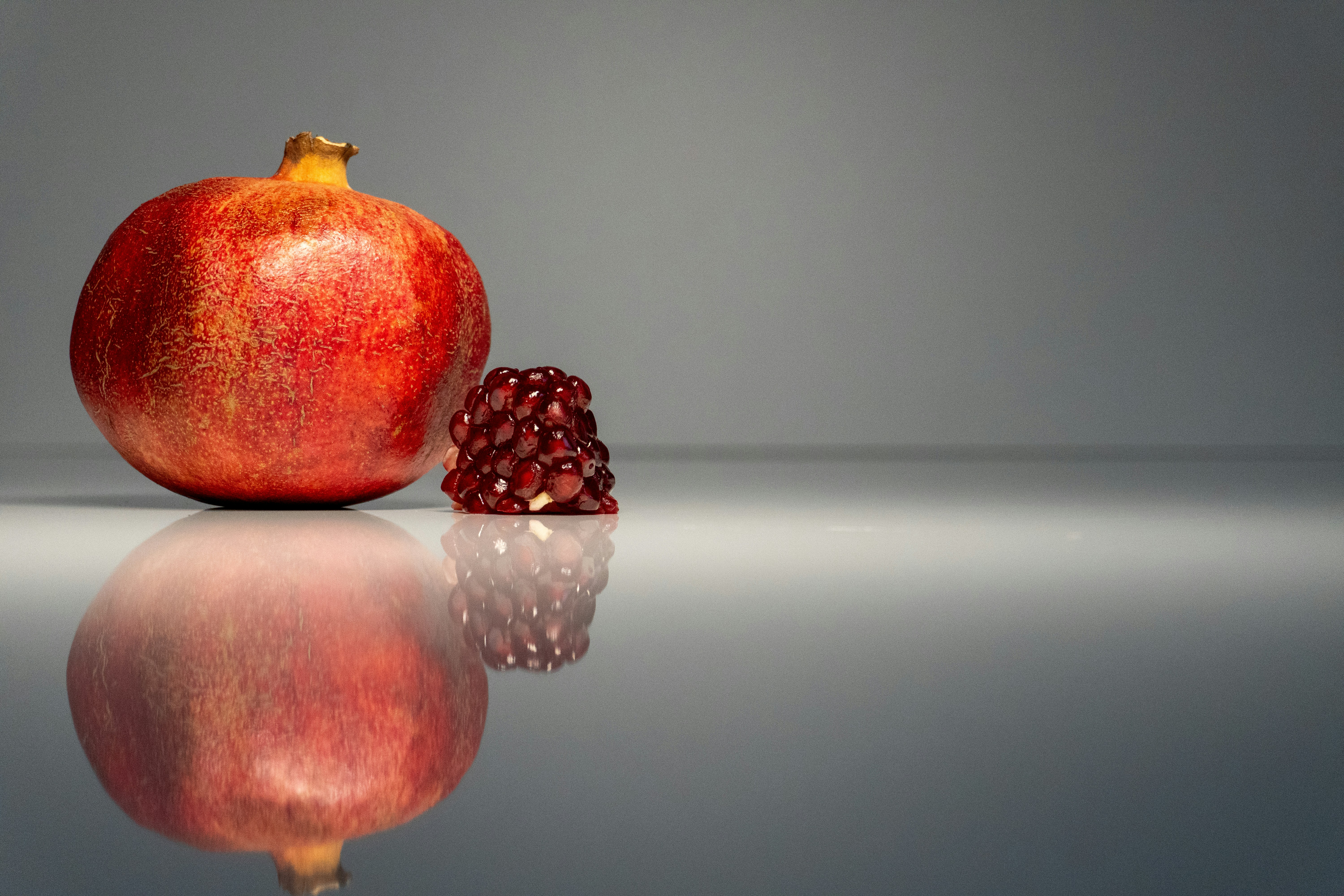 a pomegranate sitting on top of a reflective surface