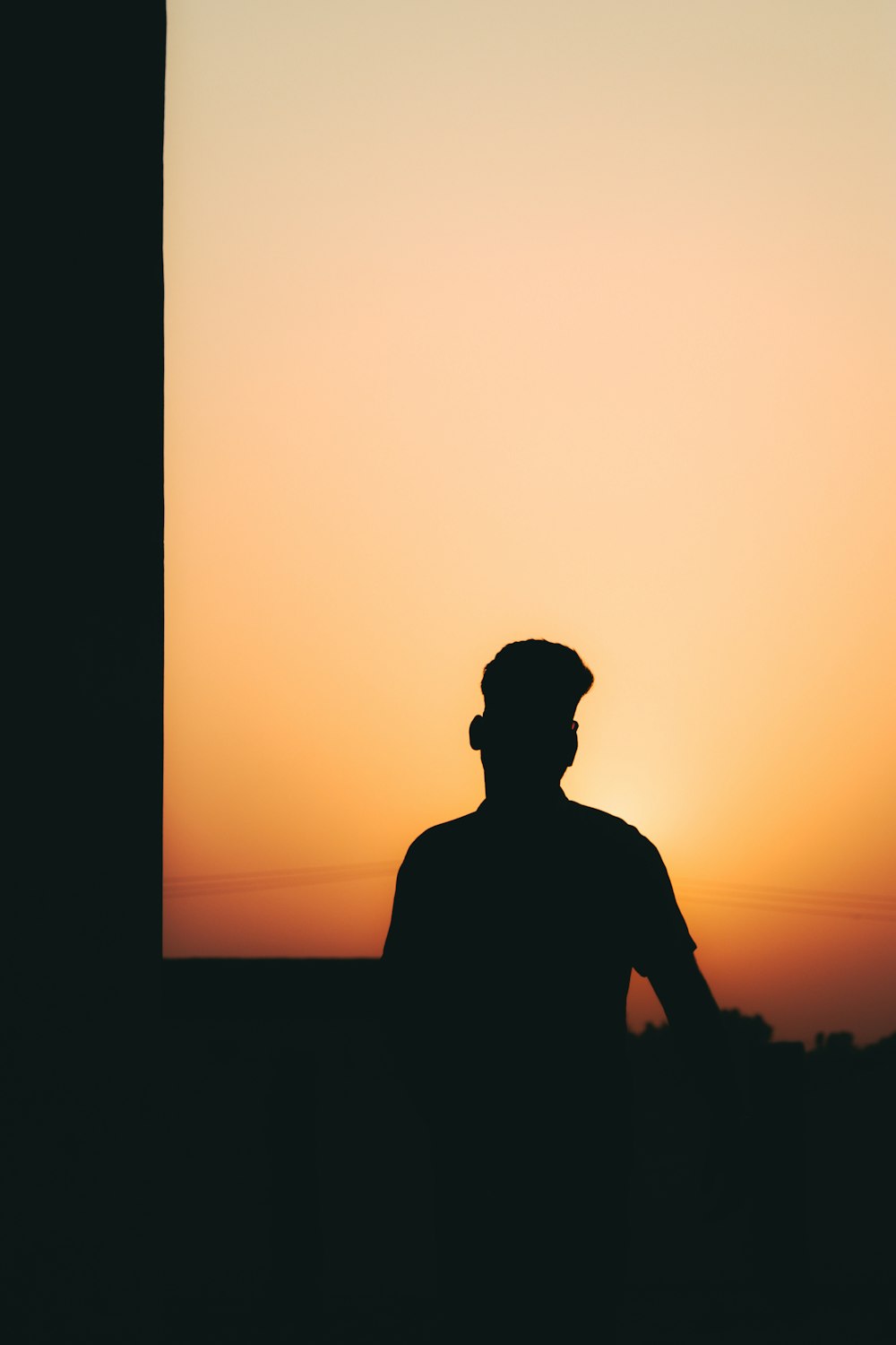 a silhouette of a man standing in front of a sunset