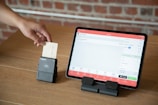 a person is holding a piece of paper in front of a tablet