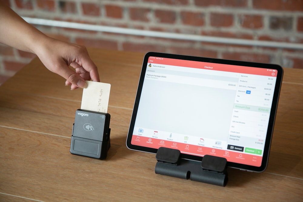 a person is holding a piece of paper in front of a tablet