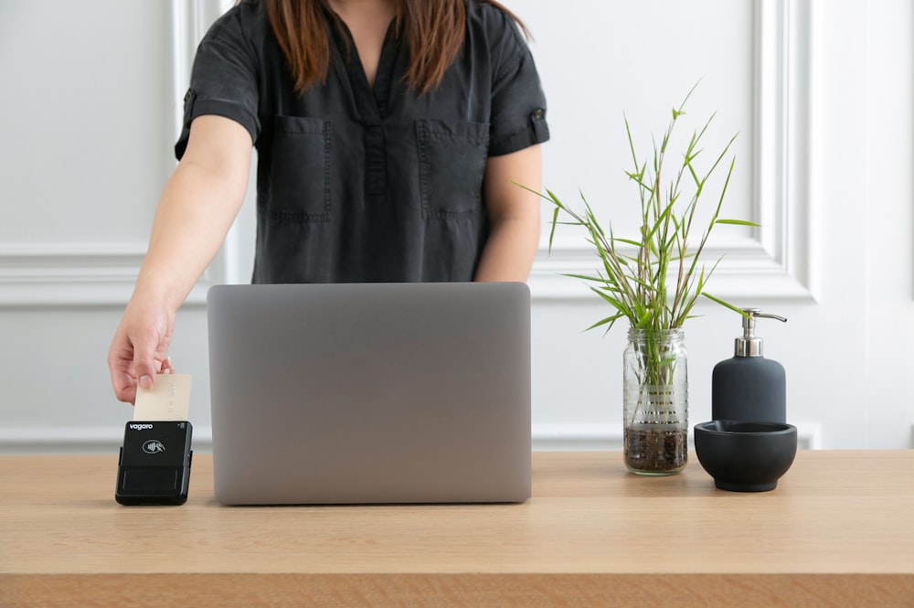 a woman standing at a desk with a laptop and a phone