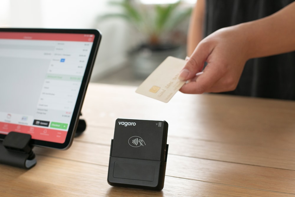 a person holding a credit card in front of a computer