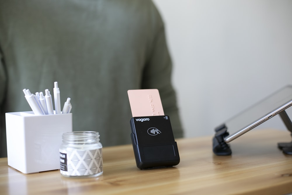 a desk with a jar of pens and a cell phone