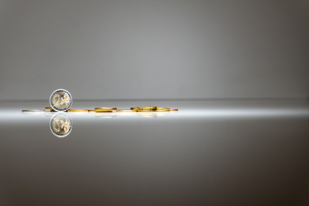 a pair of gold coins sitting on top of a reflective surface