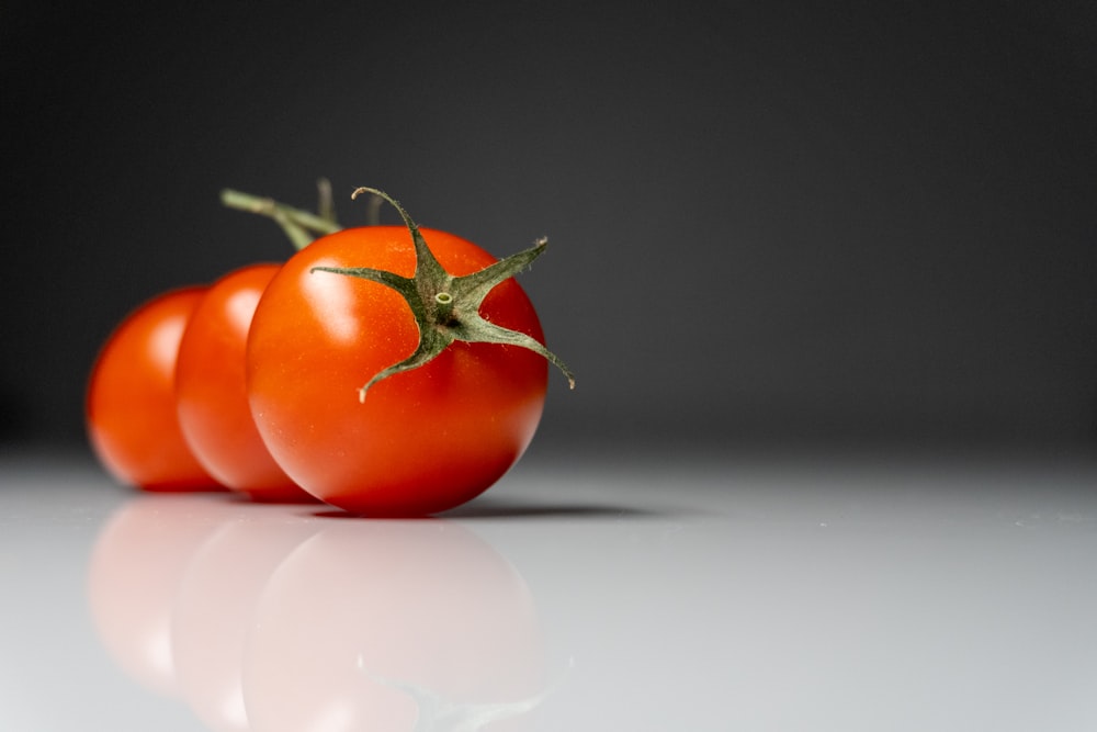 a group of three tomatoes sitting on top of a table