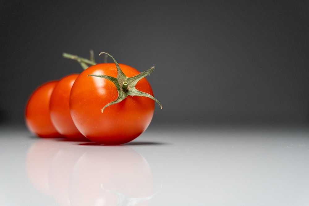 a group of three tomatoes sitting on top of a table