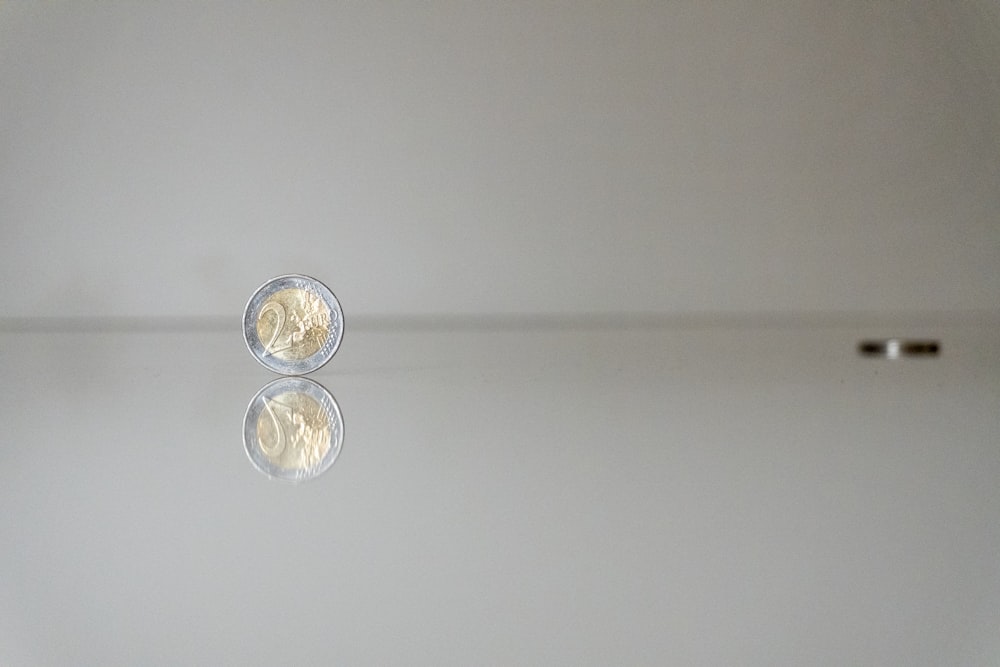 a white wall with a reflection of a coin on it