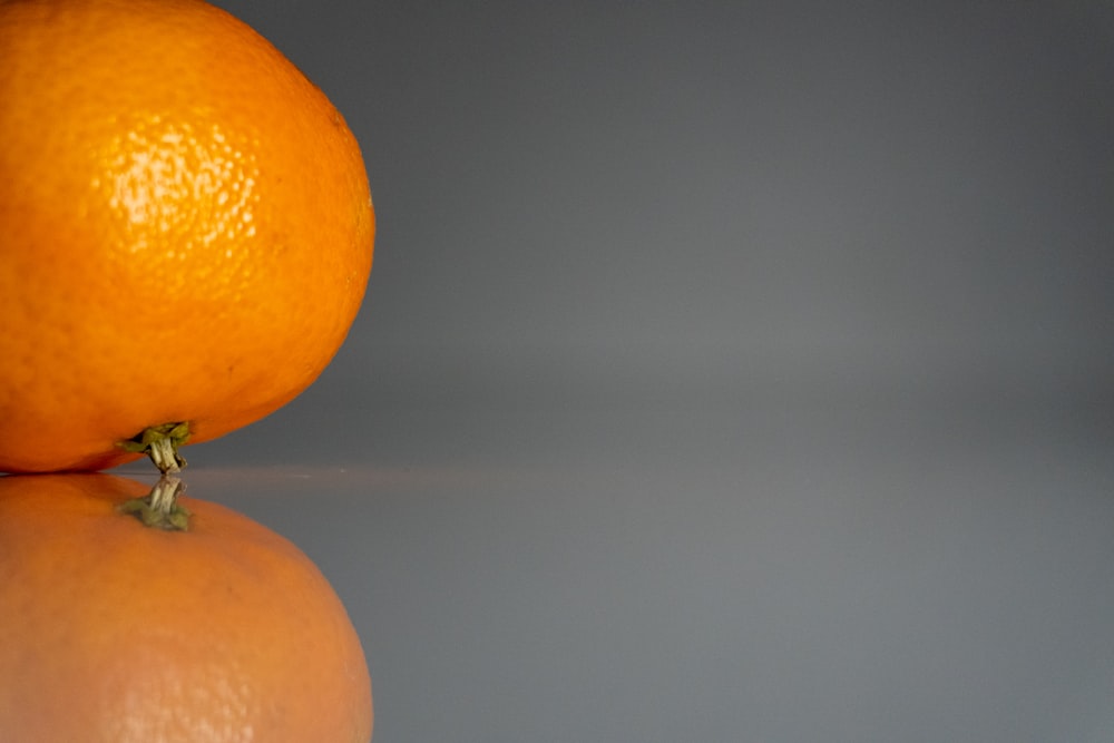 a close up of an orange on a reflective surface