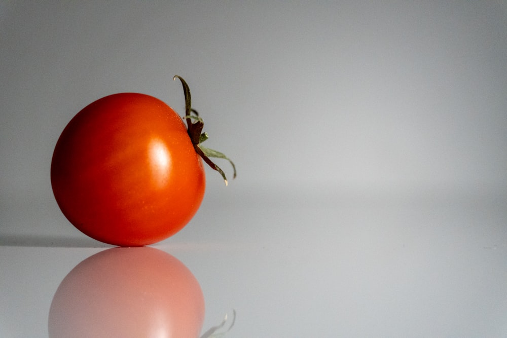 um tomate sentado em cima de uma superfície branca