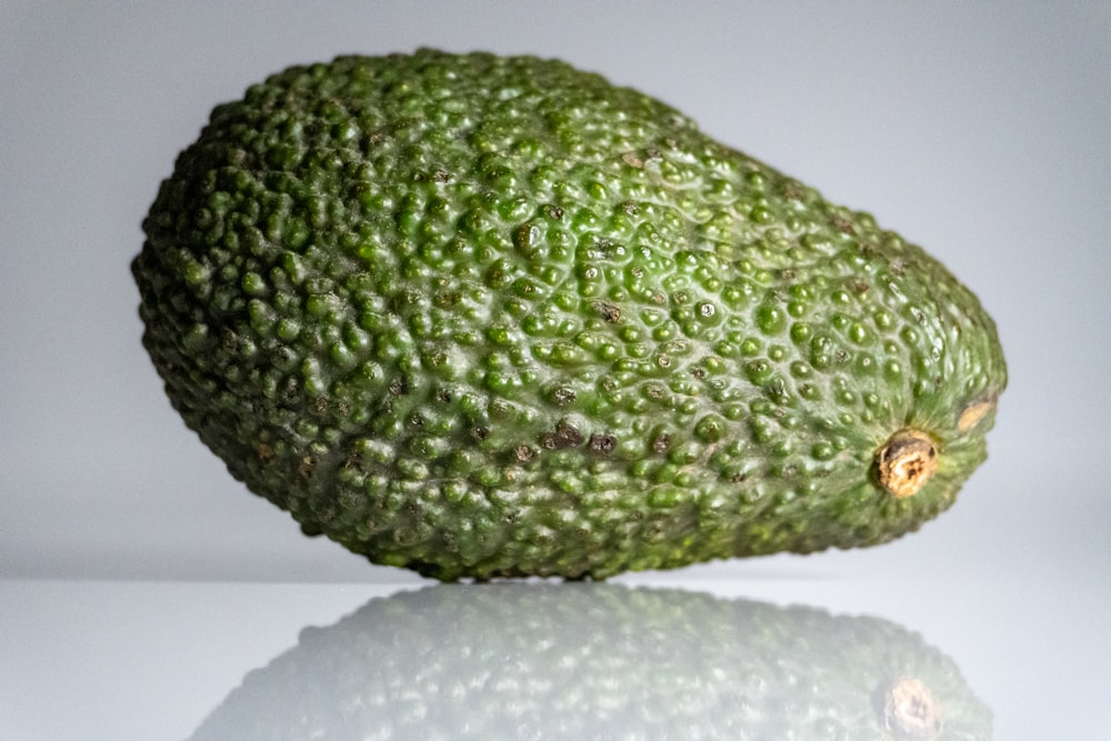 um grande abacate verde sentado em cima de uma mesa