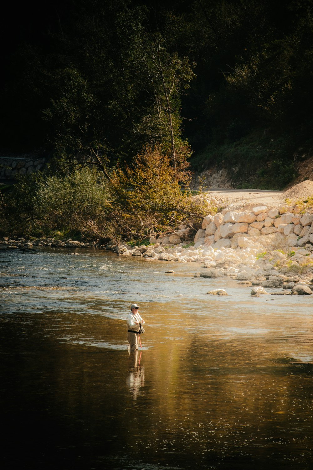 a man standing in the middle of a river holding a fish