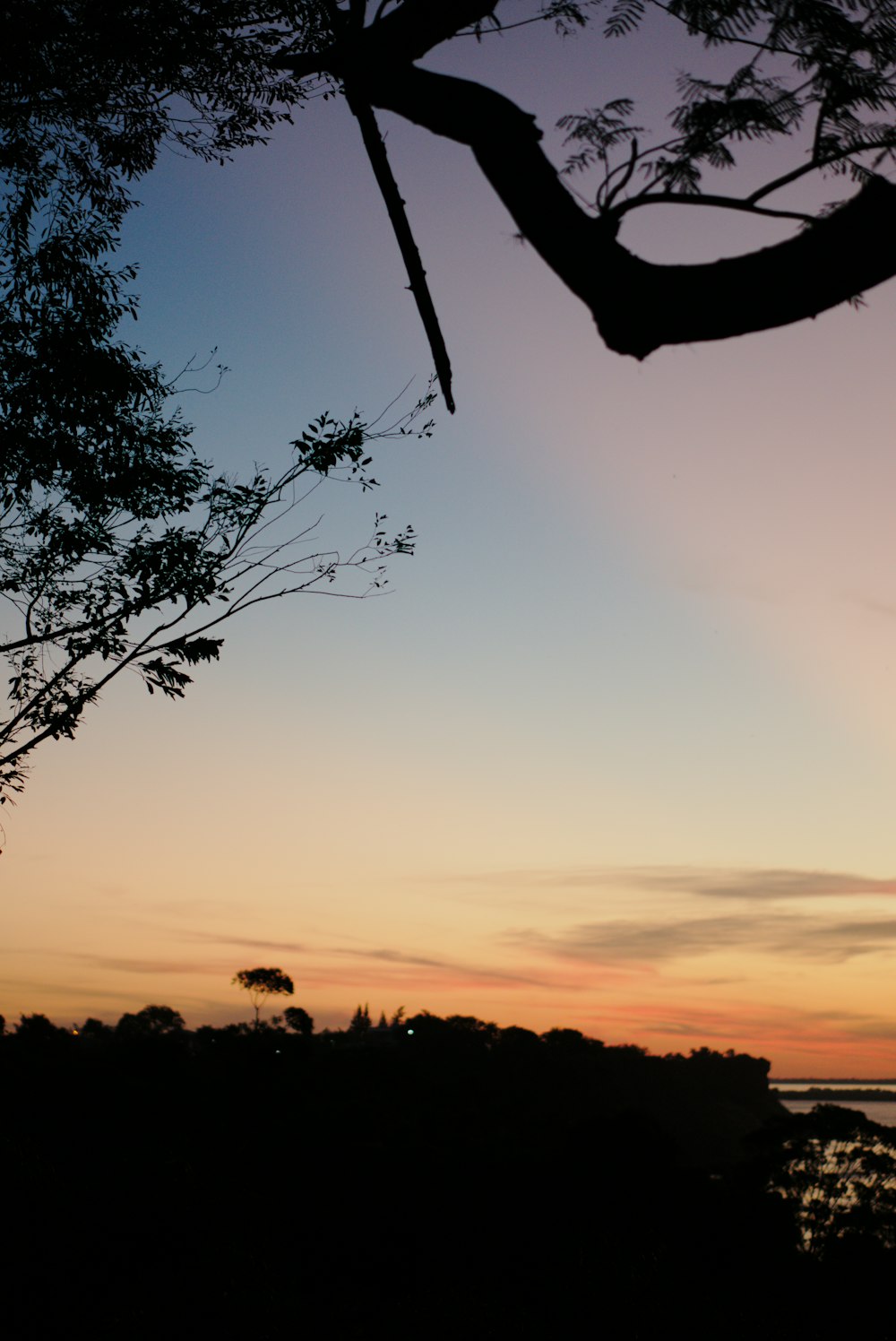 the sun is setting over the water and trees