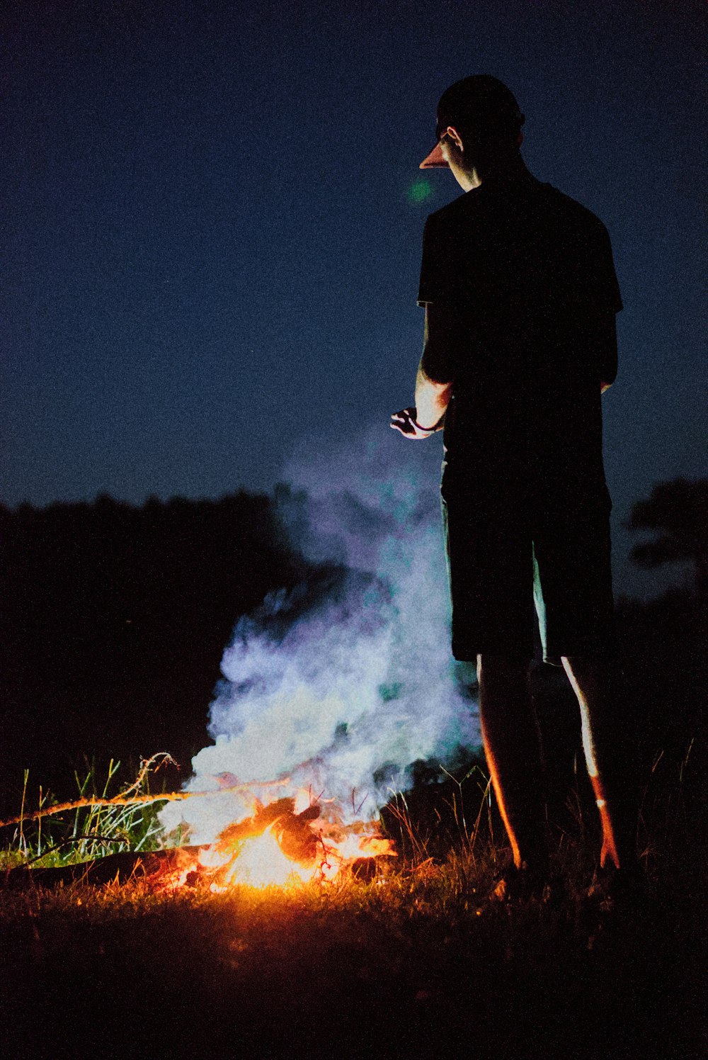 a man standing in front of a fire at night