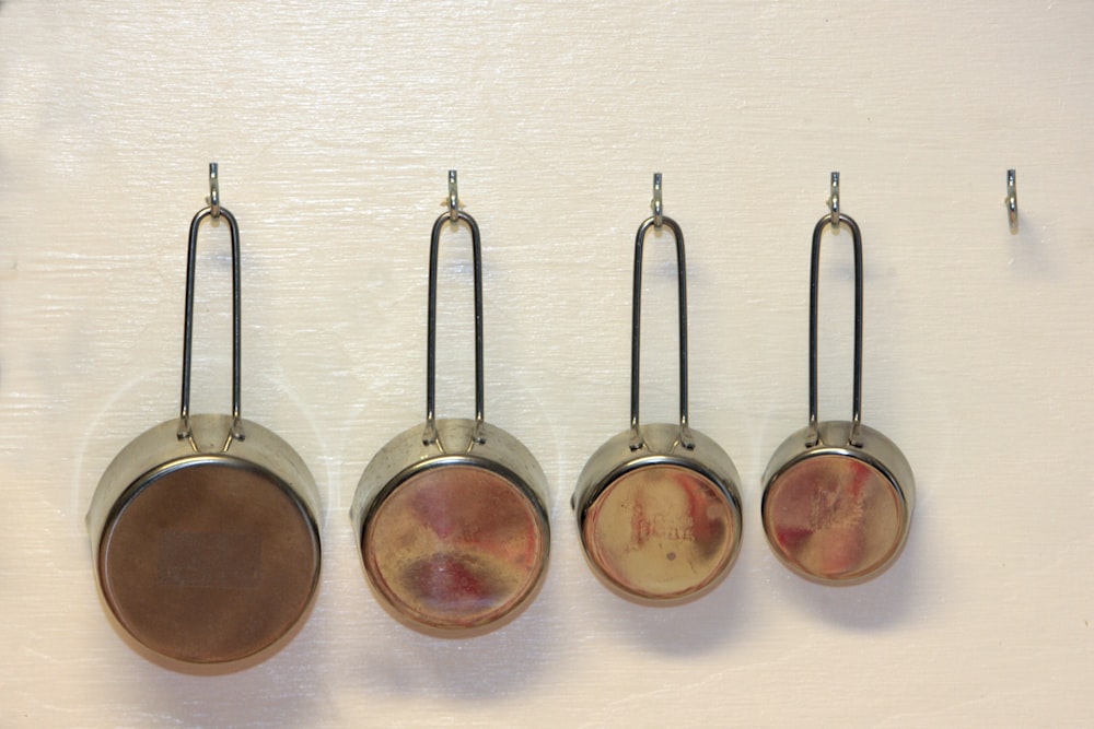 a group of four metal pots hanging from hooks