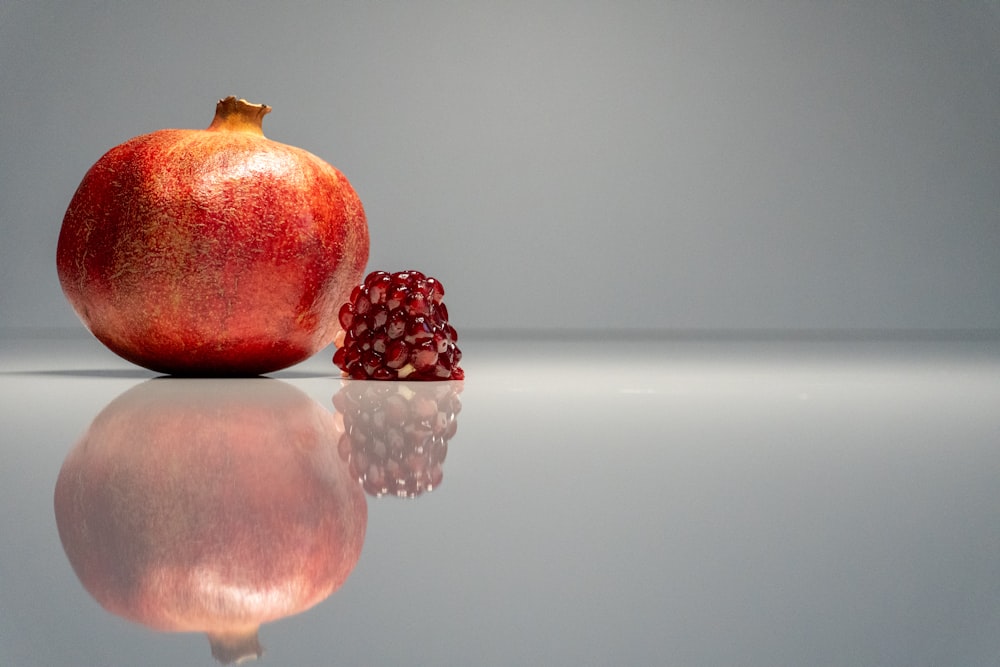 a pomegranate sitting on top of a reflective surface