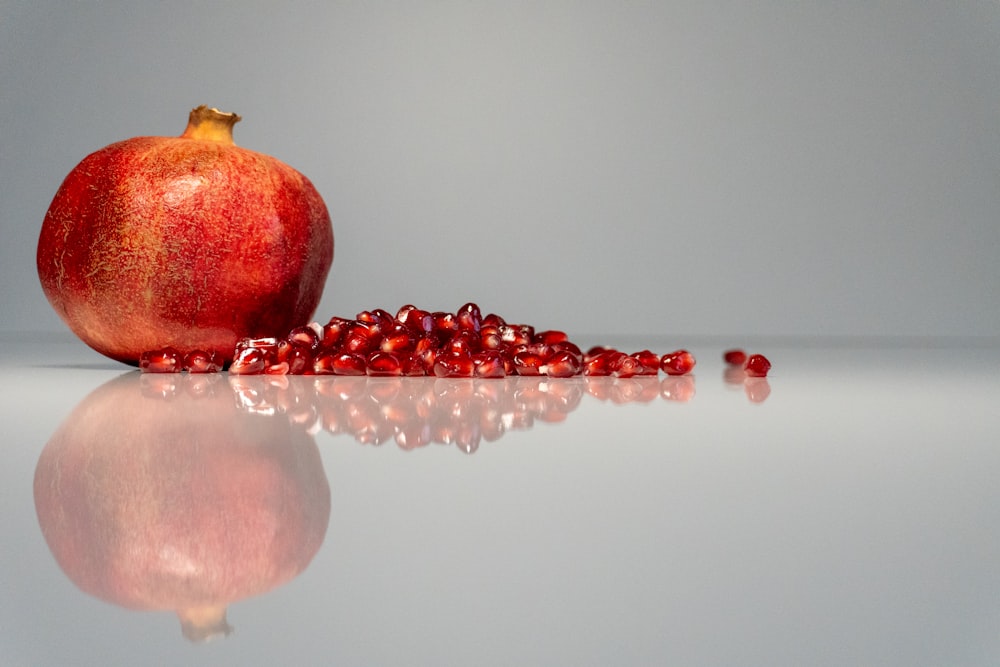a red pomegranate sitting on top of a reflective surface
