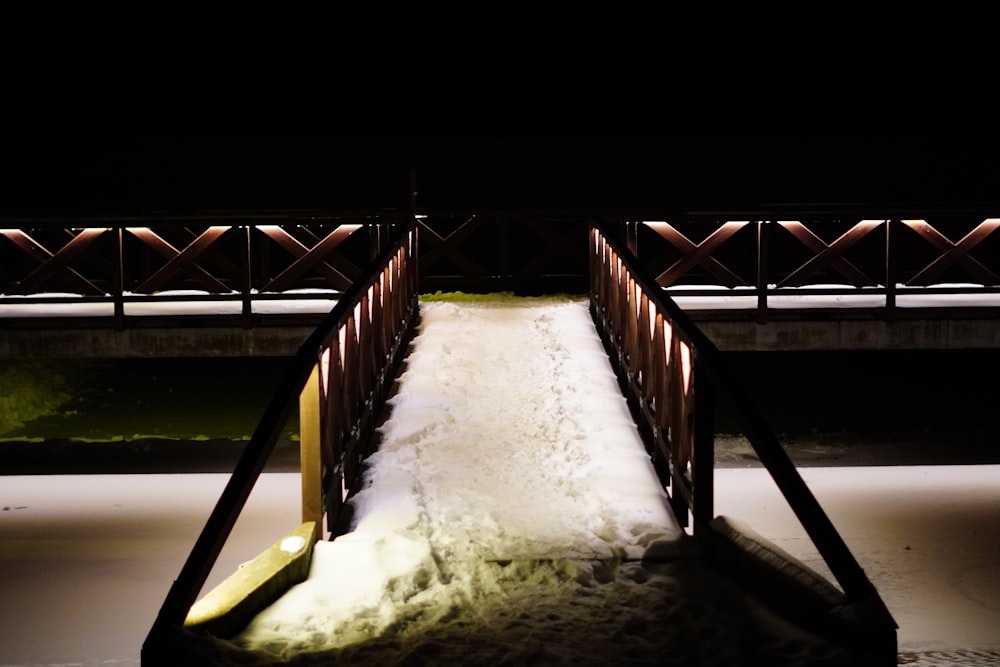 a snow covered bridge at night with snow on the ground