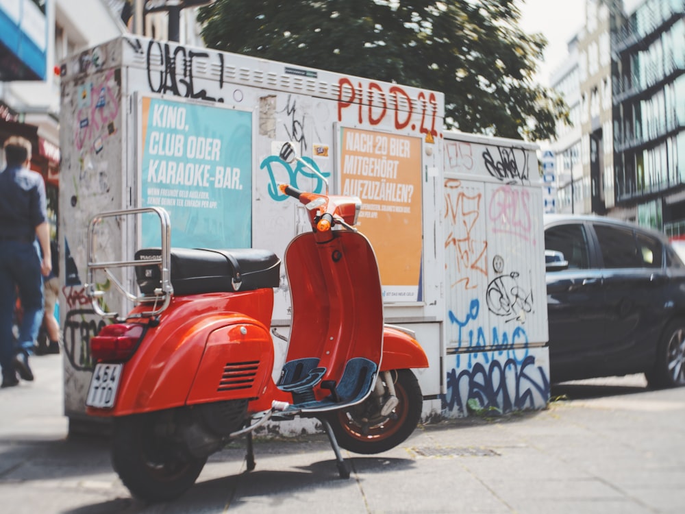 a red scooter parked on the side of a street