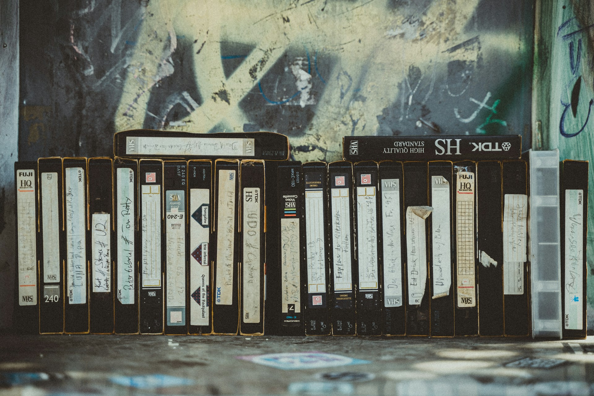 a row of records sitting next to a wall covered in graffiti