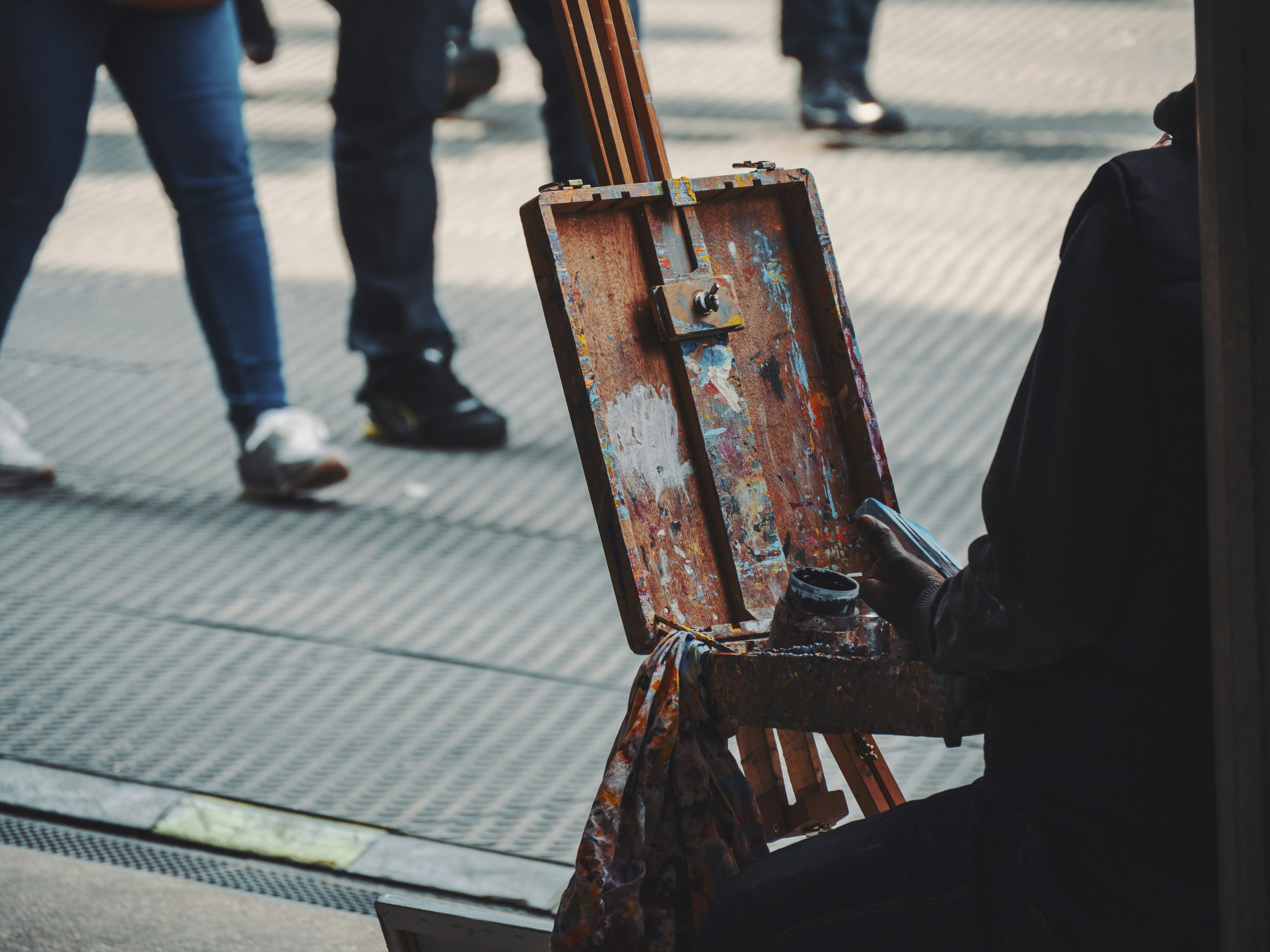 uma pessoa sentada em frente a um cavalete com uma pintura