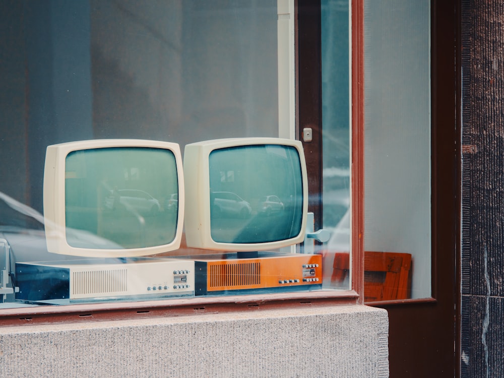 Un par de televisores viejos sentados en una ventana