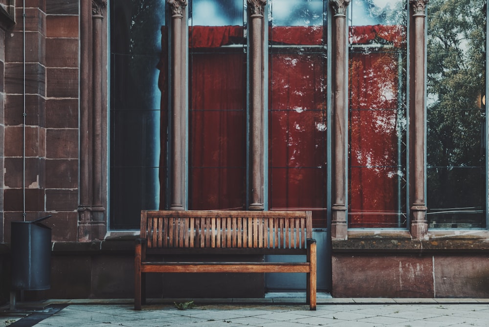 um banco de madeira sentado em frente a um edifício