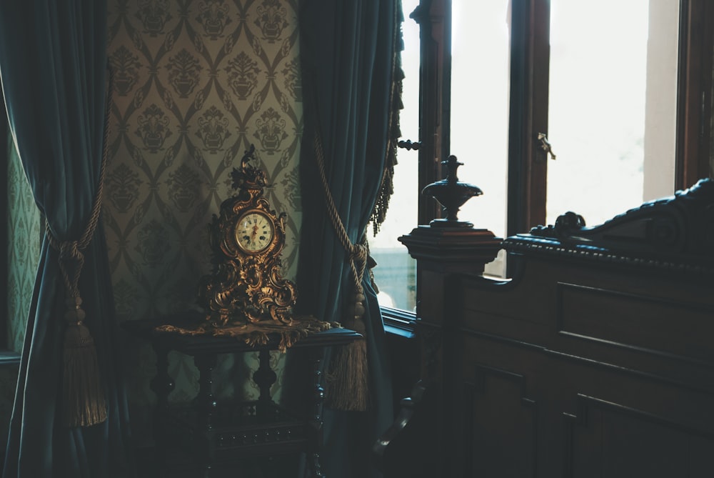 a clock sitting on top of a table next to a window