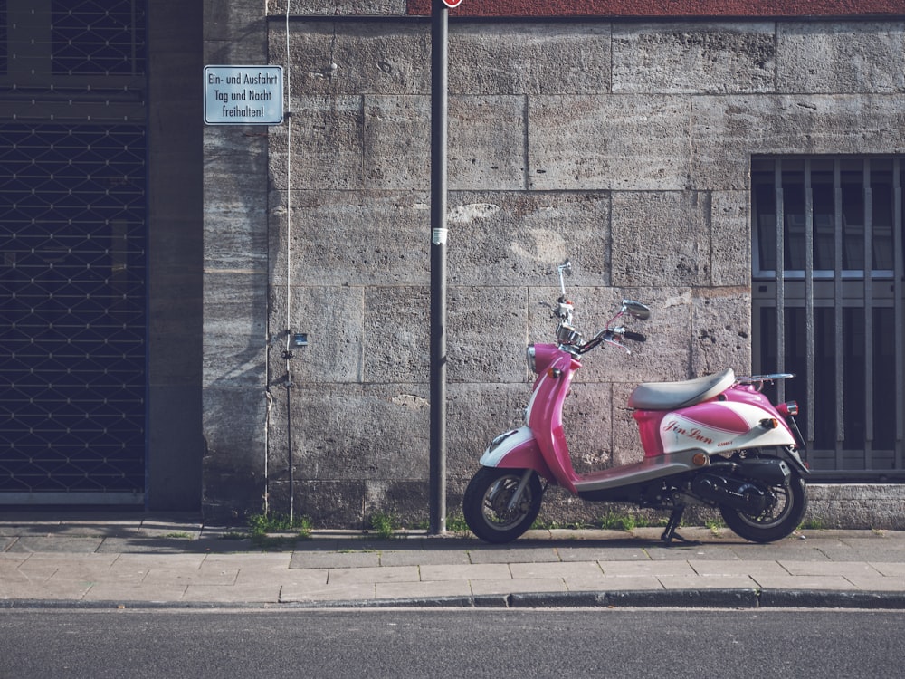 a pink scooter parked on the side of a street