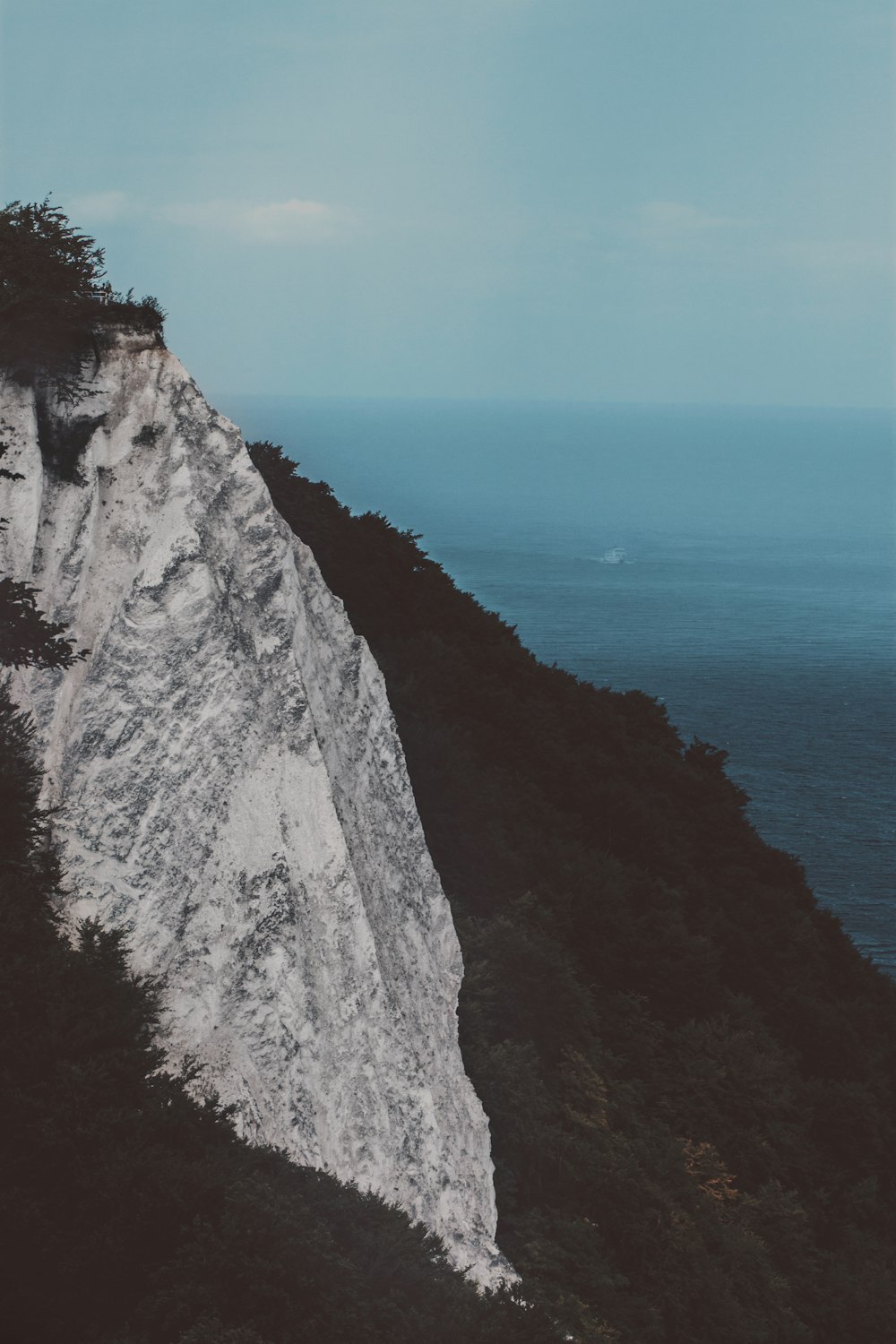 a person standing on top of a mountain next to the ocean