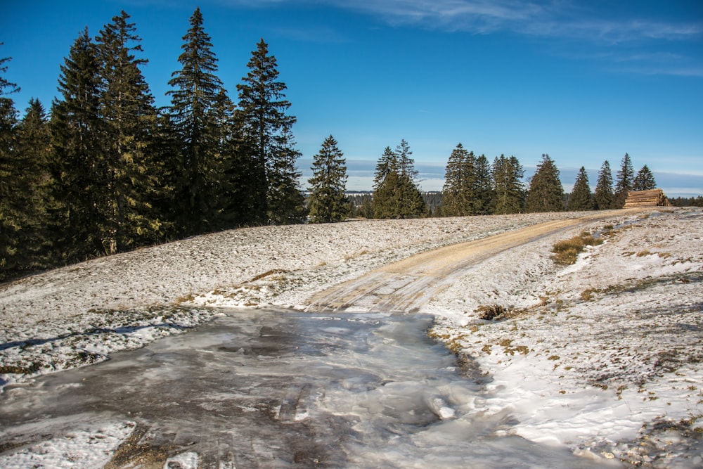 a dirt road in the middle of a snow covered field